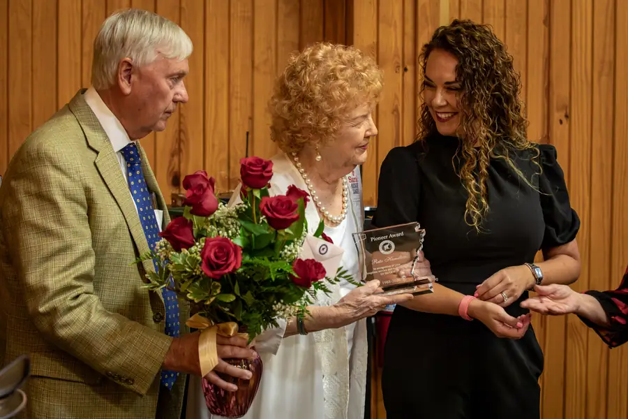 A longtime member receives roses and an engraved award during the program