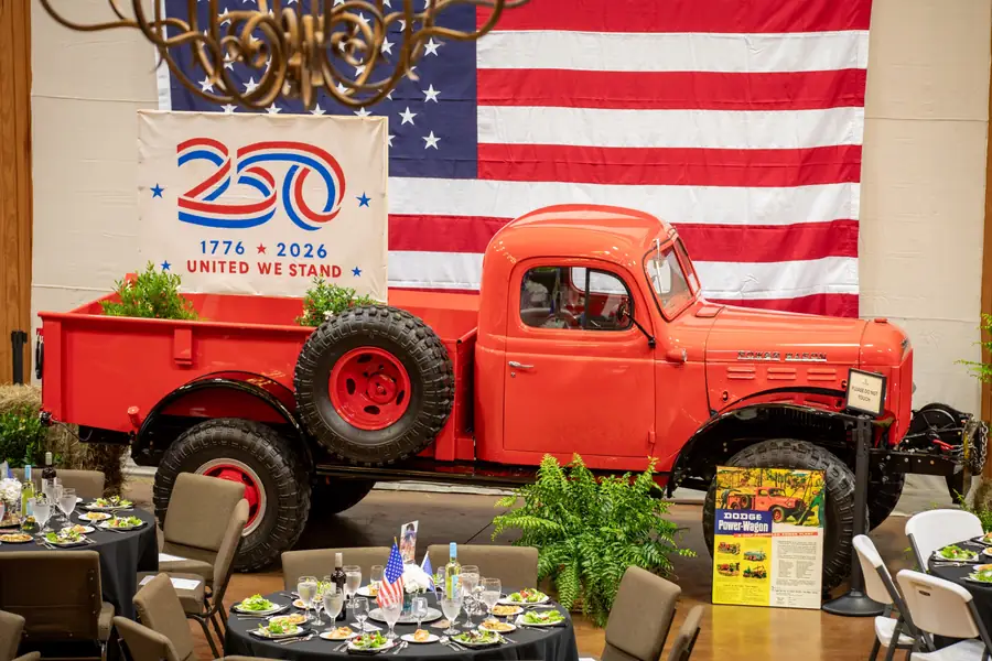 The dining hall at Legacy Ranch set for the party's Celebrating 250 dinner, with a vintage truck and a large American flag